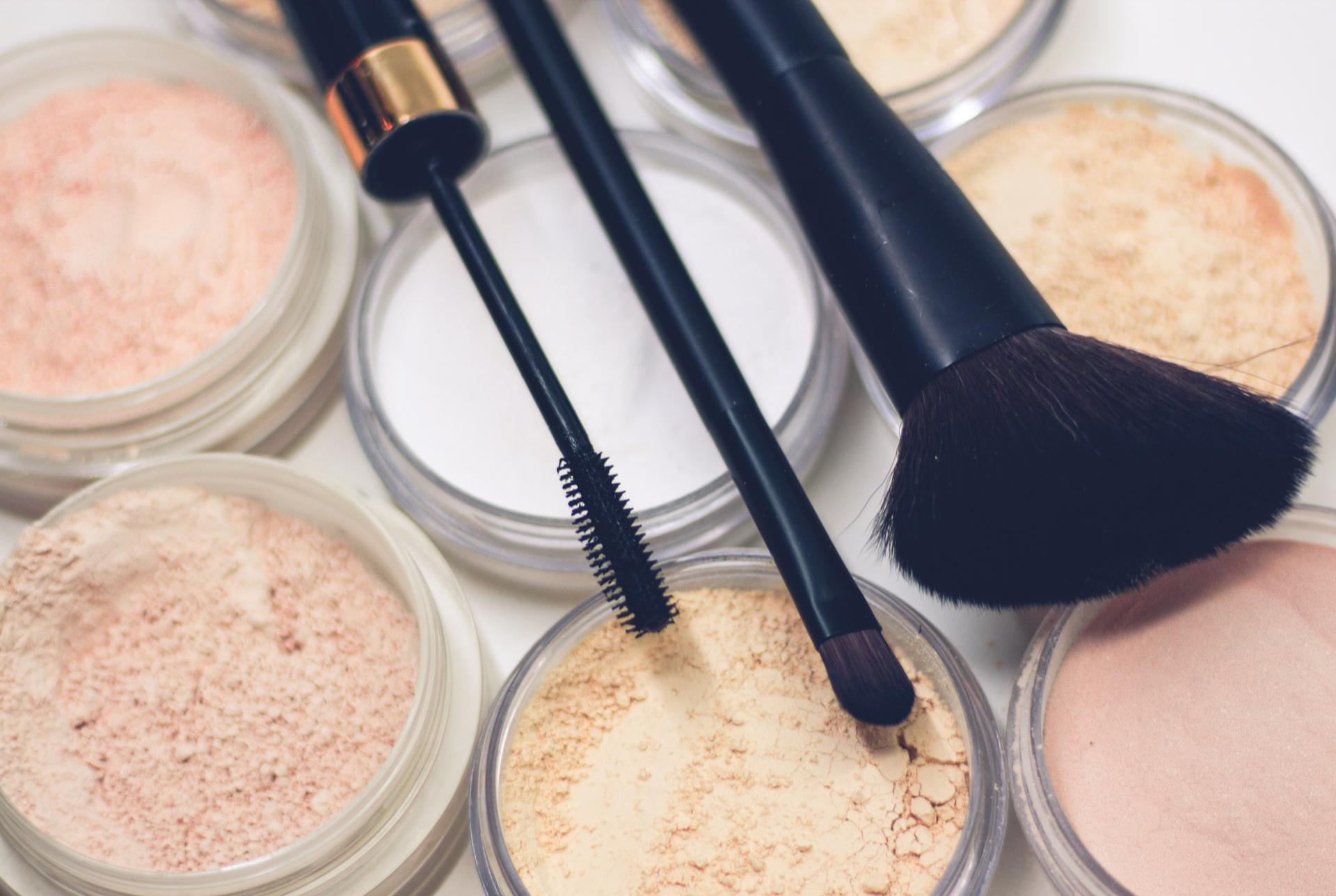 three makeup brushes on top of compact powders